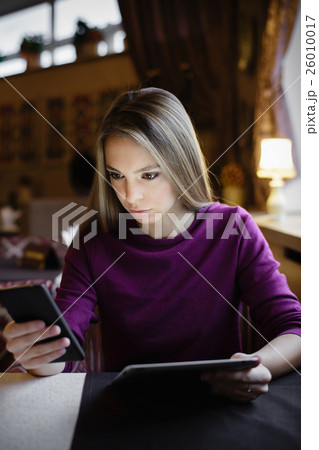 Thoughtful woman looking at smartphone Thoughtful woman looking at smartphone 26010017