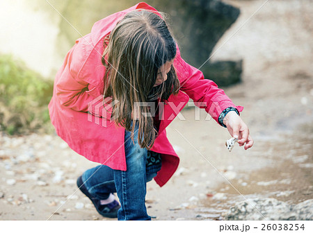 pretty little girl playing on a rock at the water's edge pretty little girl playing on a rock at the water's edge 26038254