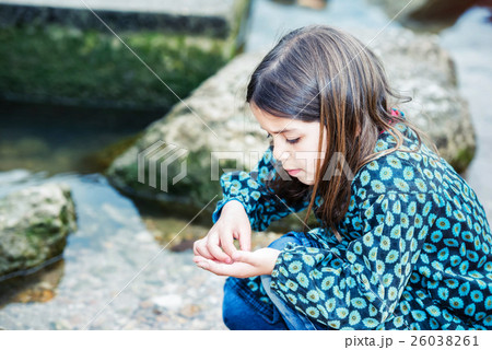 pretty little girl playing on a rock at the water's edge 26038261
