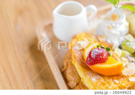 French toast with powdered sugar and a strawberry on wood table . 26049922