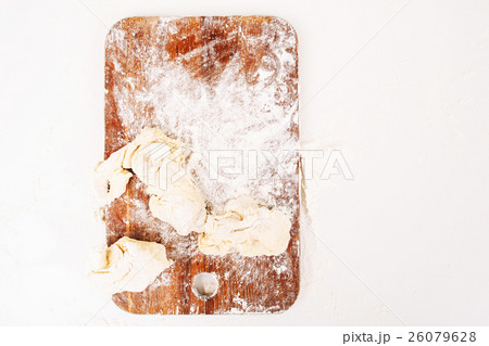 Floured cutting board with raw dough top view 26079628
