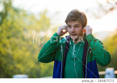 Common young man walking in the city listening to Common young man walking in the city listening to 26087573