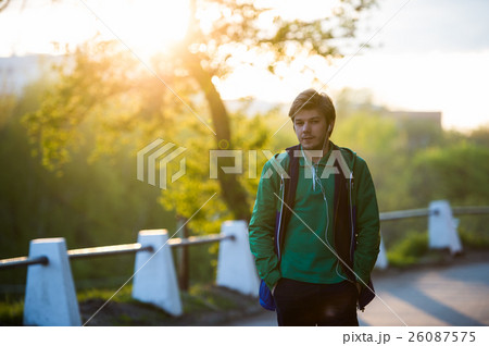 Common young man walking in the city listening to Common young man walking in the city listening to 26087575