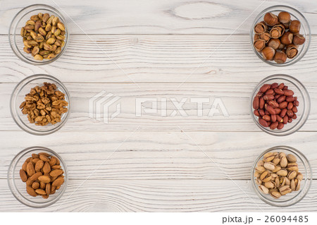 Mix nuts in a glass bowl on the old wooden table. Mix nuts in a glass bowl on the old wooden table. 26094485