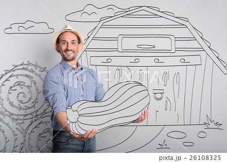Handsome glad farmer holding pumpkin. Handsome glad farmer holding pumpkin. 26108325