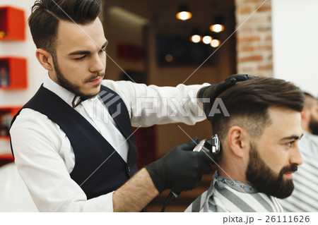 Man with dark hair doing a haircut 26111626