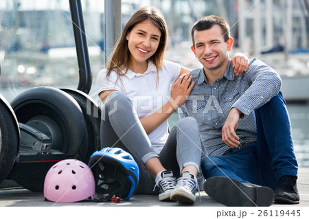Positive tourists couple relaxing near segways Positive tourists couple relaxing near segways 26119445