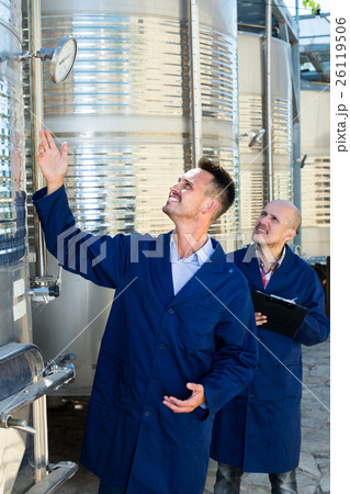 Two employees taking off data from equipment. Two employees taking off data from equipment. 26119506