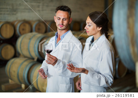 Portrait of young man and woman holding glass of wine in winery 26119581