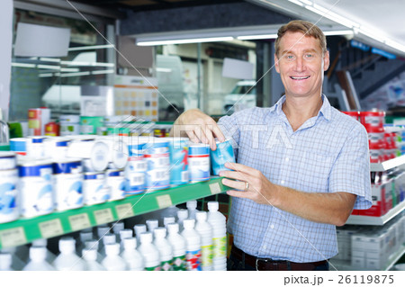 Positive man customer picking paint tin 26119875