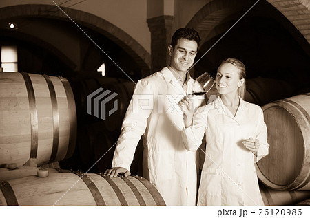 Two smiling wine house workers checking quality of product Two smiling wine house workers checking quality of product 26120986