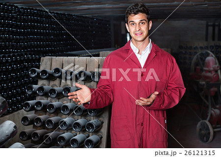 Man winery working in aging section with bottle racks in cellar Man winery working in aging section with bottle racks in cellar 26121315