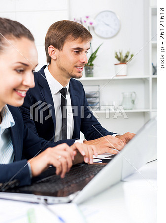 Two office workers work using laptops 26121618