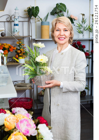 Cheerful mature blond woman selecting flowers Cheerful mature blond woman selecting flowers 26121754