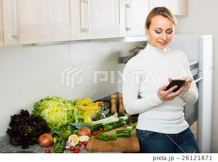 Housewife with phone at home kitchen. Housewife with phone at home kitchen. 26121871