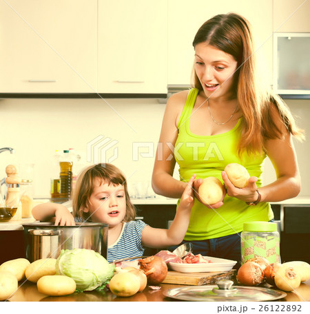 Happy woman with baby cooking with potatoes Happy woman with baby cooking with potatoes 26122892