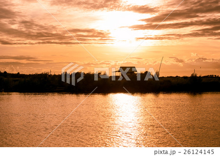 silhouette home riverside in yellow and gold sky 26124145