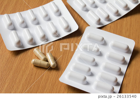 Brown capsule with white blister on wooden table Brown capsule with white blister on wooden table 26133540