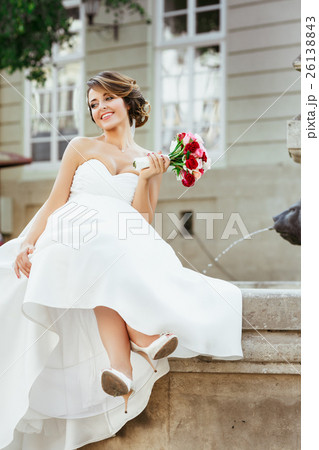 Nice bride sitting near monument and holding Nice bride sitting near monument and holding 26138843