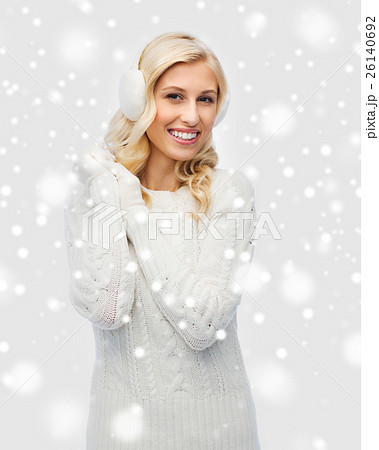 smiling young woman in winter earmuffs and sweater smiling young woman in winter earmuffs and sweater 26140692