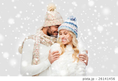 smiling couple in winter clothes hugging over snow 26141456