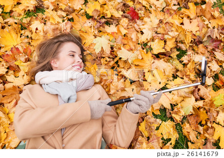 woman on autumn leaves taking selfie by smartphone 26141679