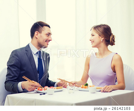 smiling couple eating sushi at restaurant 26142103