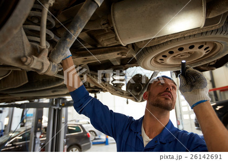 mechanic man with flashlight repairing car at shop mechanic man with flashlight repairing car at shop 26142691