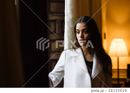 Beautiful young woman posing near a window in her bedroom Beautiful young woman posing near a window in her bedroom 26155019