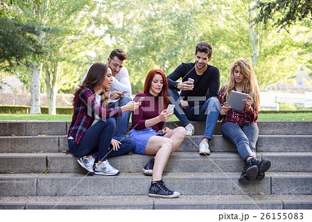 Young people using smartphone and tablet computers outdoors Young people using smartphone and tablet computers outdoors 26155083
