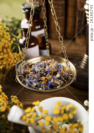 Book and Herbal medicine on wooden table  26160745