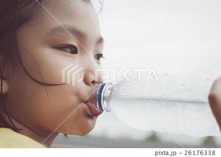 Cute girl is drinking water from plastic bottle.  26176338