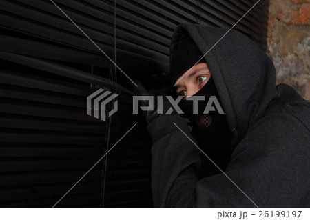 Burglar peeping into closed window 26199197