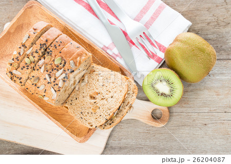 Whole wheat bread and kiwi fruit on table. 26204087