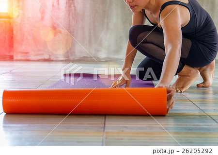 Woman rolling her mat before a yoga class Woman rolling her mat before a yoga class 26205292