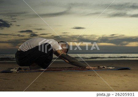 Young tattoo man practicing yoga pose on the beach Young tattoo man practicing yoga pose on the beach 26205931