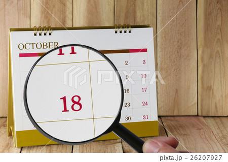 Magnifying glass in hand on calendar you can look Eighteenth date of month,Focus number Eighteen in October. 26207927