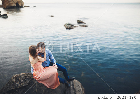 Wedding couple sitting on large stone around blue Wedding couple sitting on large stone around blue 26214130