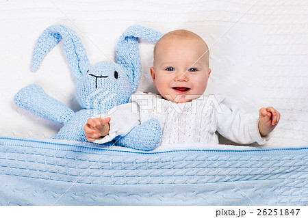 Baby boy playing with blue knitted bunny toy 26251847