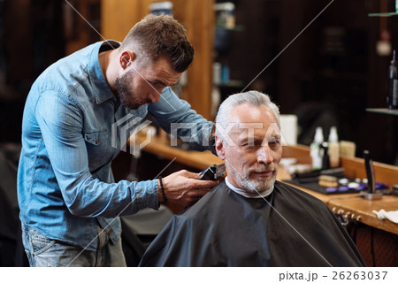 Handsome barber trimming hair of old man 26263037
