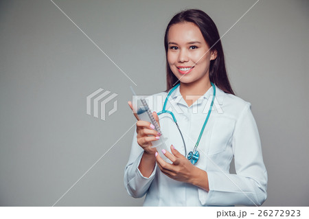 Smiling young woman doctor in white coat holding 26272923