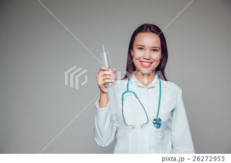 Smiling young woman doctor in white coat holding 26272955