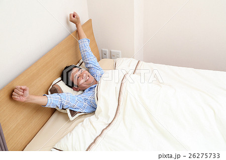 ベッドから起きる50代男性の写真素材