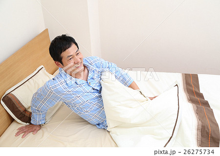 ベッドから起きる50代男性の写真素材