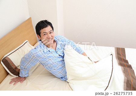 ベッドから起きる50代男性の写真素材