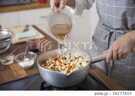 大豆と野菜を入れた鍋にだしを注ぐ女性 26277655