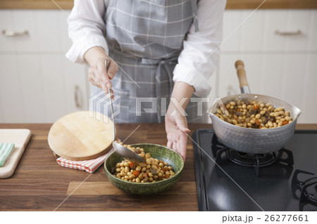 五目豆をお玉で器に盛り付ける女性 26277661