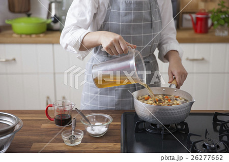 大豆と野菜を入れた鍋にだしを注ぐ女性 26277662
