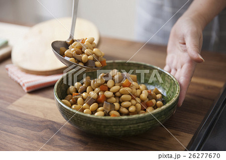 五目豆をお玉で器に盛り付ける女性 26277670