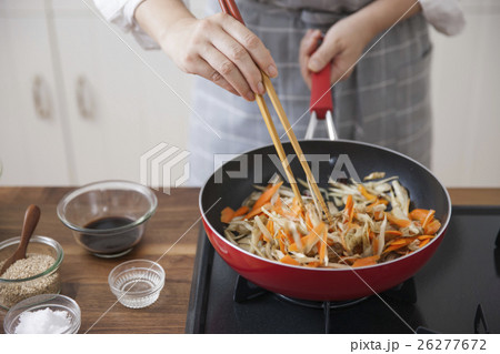 フライパンでゴボウとニンジンを炒める女性 26277672